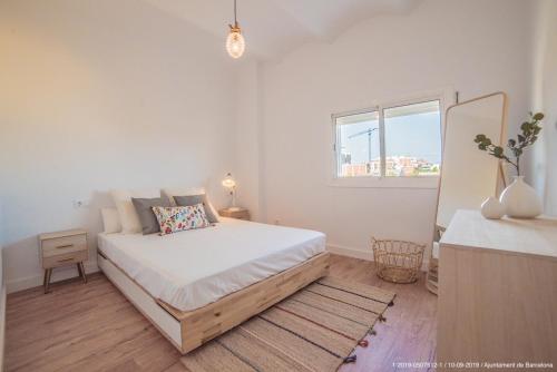 a white bedroom with a bed and a window at Poblenou 3bd 5 min to the Beach in Barcelona