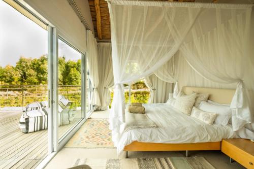 a bedroom with a canopy bed and a balcony at Stonehaven Eco Cabins in Hermanus