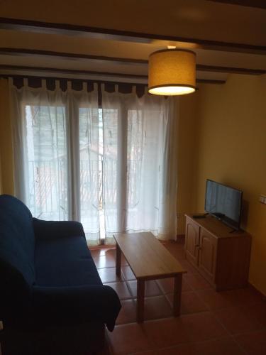 sala de estar con sofá, mesa y TV en Valdelinares Apartamentos, en Valdelinares