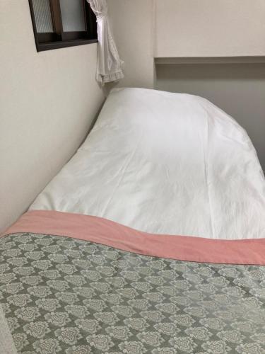 a bed with a white comforter on top of a floor at GreenHotel in Tokyo