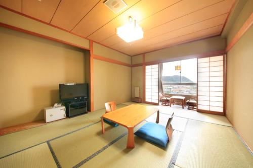 ein Wohnzimmer mit einem Tisch und einem TV in der Unterkunft Boso Shirahama Umisato Hotel in Minamiboso