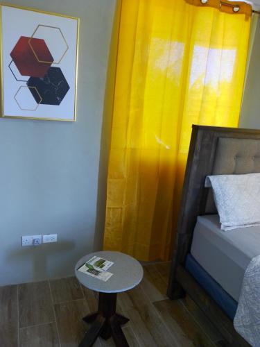 a small table in a room with a bed and a yellow curtain at 2 Bedroom Residential Rental Unit in Paix Bouche