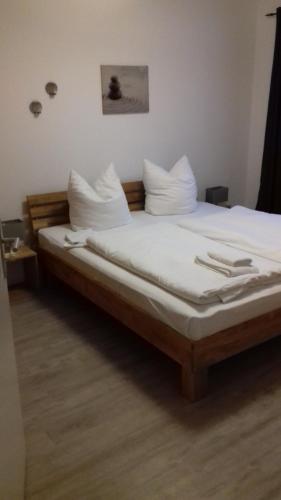 een slaapkamer met een bed met witte lakens en kussens bij Strandidyll in Zempin