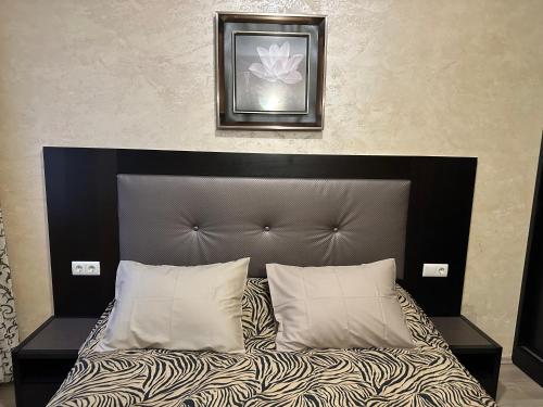 a bed with a black headboard and white pillows at Apartments & Rooms Royal Plaza in Borovets