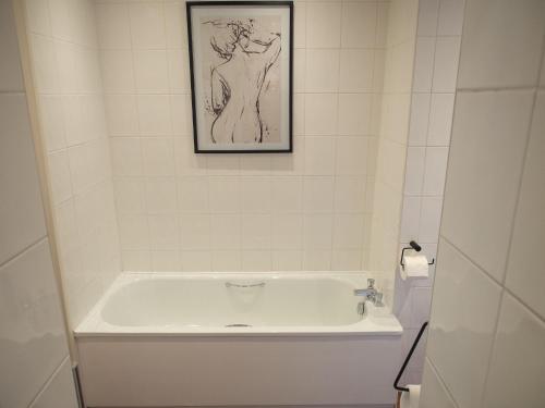 uma banheira na casa de banho com uma fotografia na parede em The Beeches - Chatsworth Apartment No 1 - Sleeps 4 em Baslow