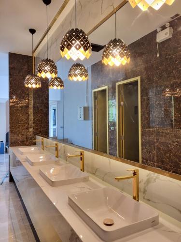 a row of sinks in a public restroom with lights at S3 Siam Bangkok Hotel in Bangkok