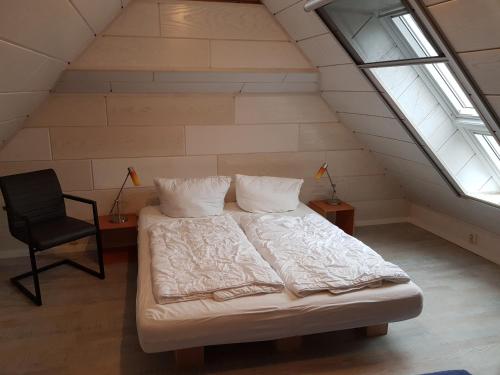 ein Schlafzimmer mit einem Bett und einem Stuhl im Dachgeschoss in der Unterkunft "Blick auf Vilm", Neuendorf in Putbus