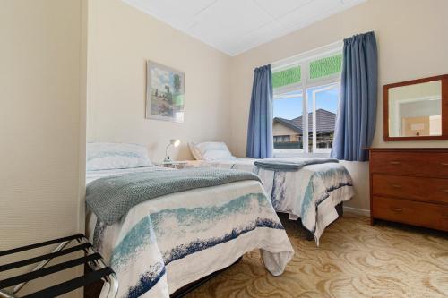 泰晤士的住宿－Whare Nui on Rennie - Thames Holiday Home，一间卧室设有两张床和窗户。