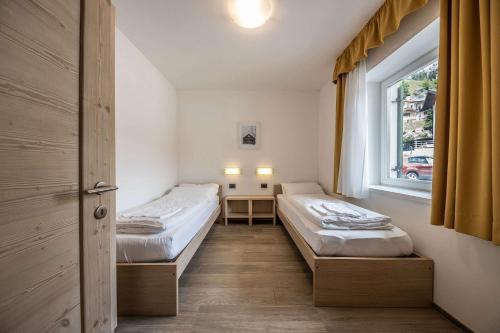 two beds in a room with a window at Appartamenti Stefan in Campitello di Fassa