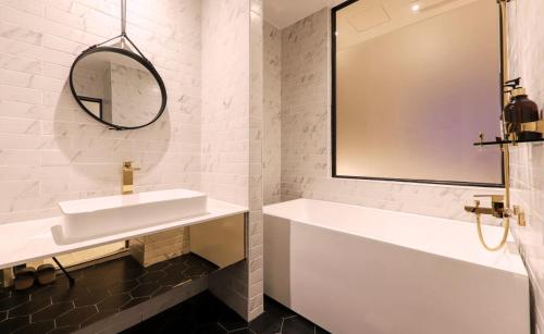 a bathroom with a sink and a tub and a mirror at Brown Dot Hotel Yangsan Seochang in Yangsan