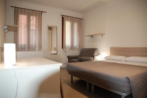 a bedroom with a bed and a couch and a chair at Hotel Lugano Torretta in Marghera