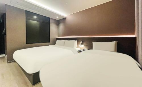 two white beds in a room with a tv at Brown Dot Hotel Yangsan Seochang in Yangsan