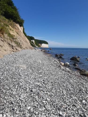 a rocky beach next to the ocean on a sunny day at Villa Bella Vista - Meerblick 4 in Sassnitz