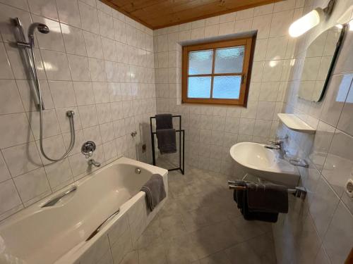Design Apartment Westendorf by Alpine Host Helpers في وستندورف: حمام أبيض مع حوض ومغسلة