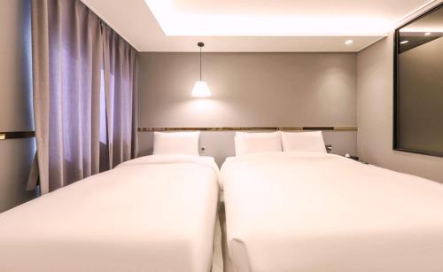 two twin beds in a room with a tv at Brown Dot Hotel Yangsan Seochang in Yangsan