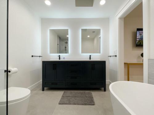 a bathroom with a black vanity and two mirrors at @ Marbella Lane – Contemporary Sophisticated Home in Sunnyvale
