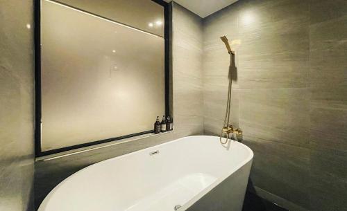 a bath tub in a bathroom with a large mirror at Brown Dot Hotel Yangsan Seochang in Yangsan