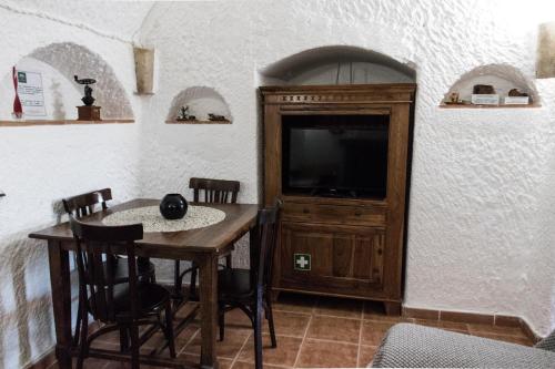a dining room with a table and a tv at Casa Cueva Picoesquina in Guadix
