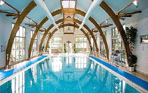 a large swimming pool in a building with a ceiling at Joli Mobil home N°11, 4ch tout confort et spacieux in Gastes