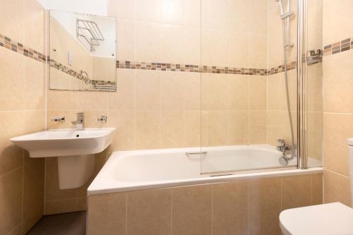 a bathroom with a sink and a tub and a toilet at ALTIDO 5 Bedroom Apt near Meadows and George Square in Edinburgh