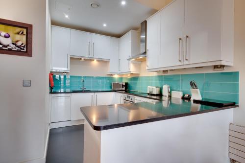 a kitchen with white cabinets and blue tiles at Crown Apartments 3B Ideal Choice for City Breaks in Newcastle upon Tyne