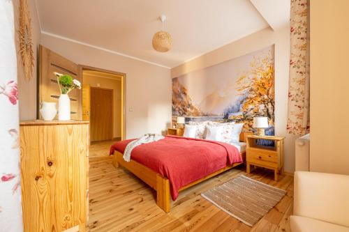 Un dormitorio con una cama roja y una pintura en la pared en Apartament Pod Orłem, en Zakopane