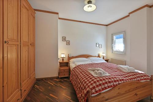 1 dormitorio con 1 cama grande con manta roja en Residence Hotel Casa Metz, en Santa Cristina Valgardena
