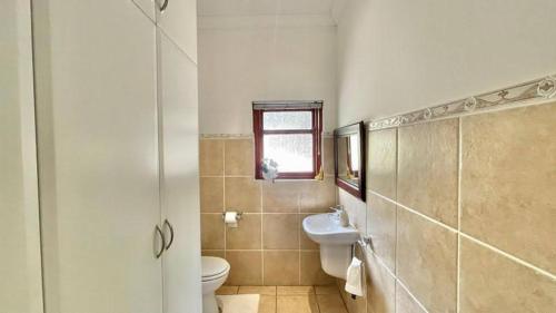 a bathroom with a sink and a toilet and a window at 27 @ Wozani Ridge in Hibberdene