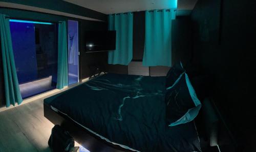 1 dormitorio con cama negra y ventana en Au nid d'amour, en Bellencombre