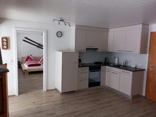 una cocina con armarios blancos y una habitación con sofá en Chalet Pfyffer - Mountain view en Grindelwald