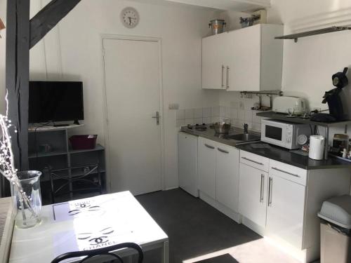 une cuisine avec des armoires blanches et un micro-ondes dans l'établissement jolie studio centre ville d'arras, à Arras