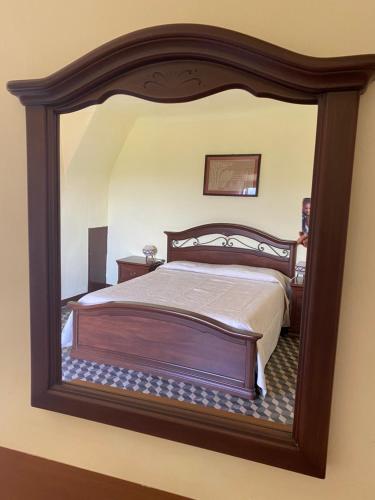 ein Schlafzimmer mit einem großen Holzbett im Spiegel in der Unterkunft Casa al vecchio mulino in Sperlinga
