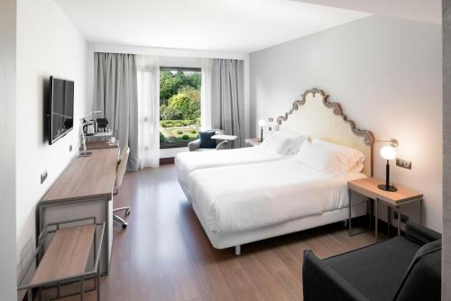 a hotel room with a bed and a desk and a television at Palacio de Aviles Affiliated By Melia in Avilés