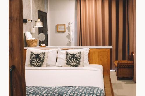 two cats are sitting on top of a bed at Sleepy House Chiang Rai in Chiang Rai
