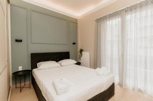 Schlafzimmer mit einem Bett mit weißer Bettwäsche und Kissen in der Unterkunft Satus Finem Egnatia's Luxury Apartment in Thessaloniki
