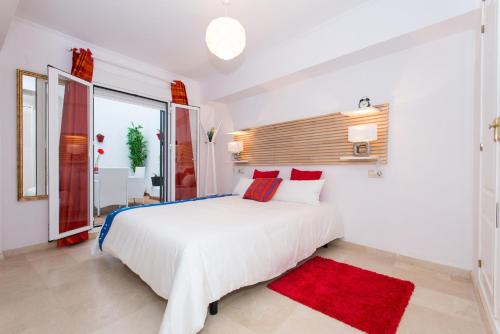 a white bedroom with a large bed and a red rug at The Zentral Suites & Apartments in Seville