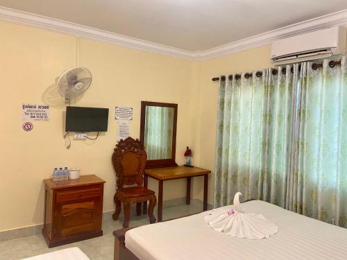 a bedroom with a bed and a desk and a fan at Savet Guesthouse in Stœ̆ng Trêng