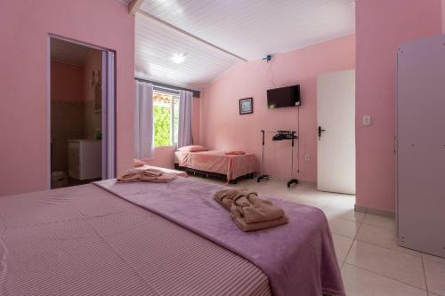 Un dormitorio con paredes rosas y una cama con toallas. en Suítes Valdira, en Arraial d'Ajuda