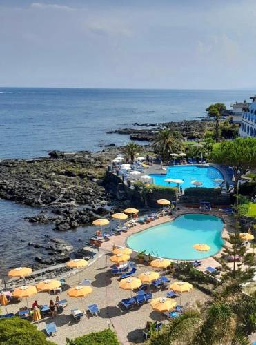 an aerial view of two pools with umbrellas and the ocean at Hotel Nike in Giardini Naxos