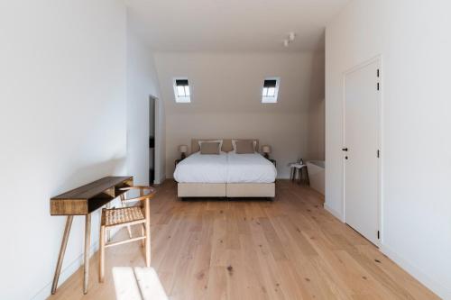 a bedroom with a white bed and a wooden floor at Duisbeke Logies in Oudenaarde