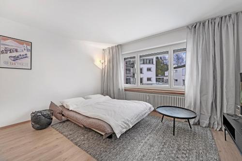 a bedroom with a bed and a table and a window at Abitaziun Belmunt 103 - St Moritz "LOGA ELEGANCE APARTMENT" in St. Moritz