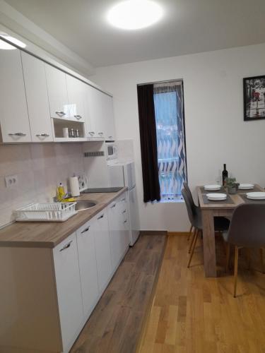 a kitchen with white cabinets and a table and a window at KONAK ViLA MIRKOVIĆ in Soko Banja