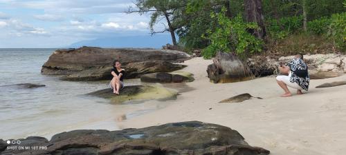 a man and a woman sitting on rocks on a beach at Bebe Homestay Phu Quoc in Phu Quoc