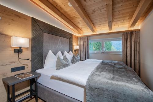sypialnia z dużym białym łóżkiem i oknem w obiekcie Hotel Alpina Wellness & Spa Resort w mieście Kössen