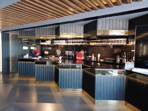 a restaurant with a bar with people preparing food at Al Qurum Resort in Muscat
