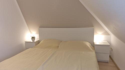 a white bedroom with a bed with two night stands at Appartement im Silwai 4 in Westerland