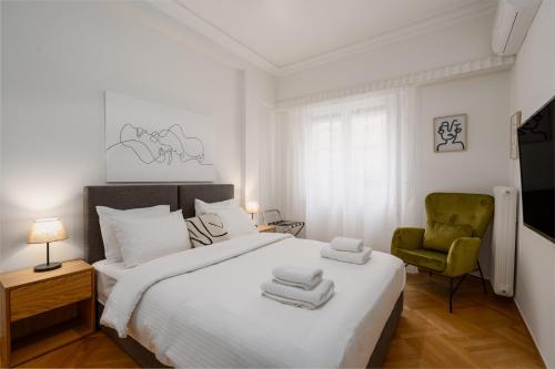 a bedroom with a white bed and a green chair at Lycabettus Residence in Athens