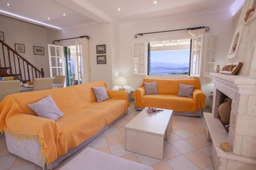 a living room with an orange couch and a fireplace at Villa Ftelias by Villa Plus in Ágios Stéfanos