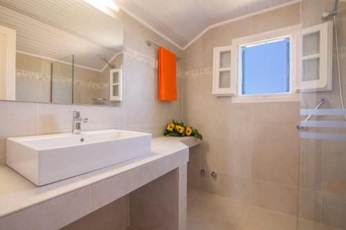 a bathroom with a white sink and a window at Villa Ftelias by Villa Plus in Ágios Stéfanos