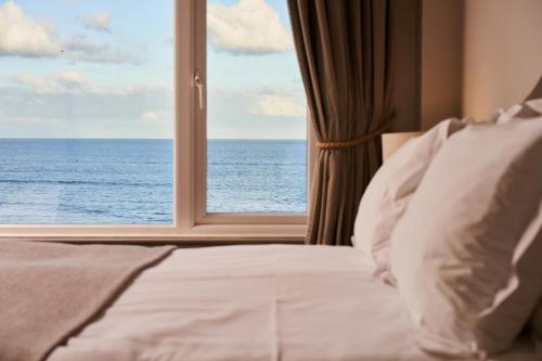a bedroom with a window looking out at the ocean at Pedn-Olva in St Ives